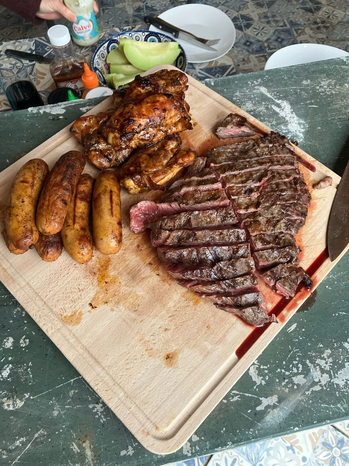 Eigen BBQ overzicht: kip, worst en grote steak op snijplank